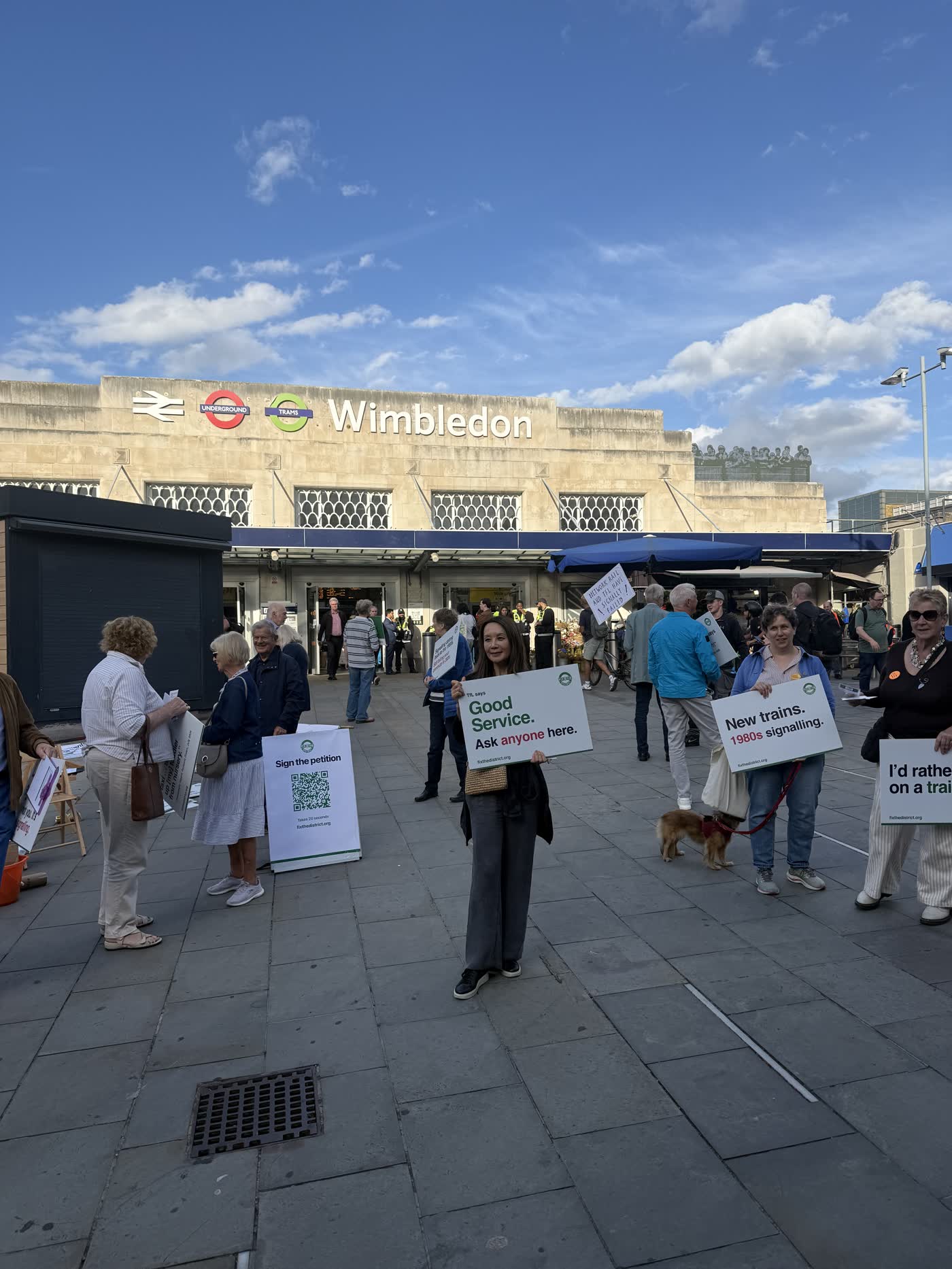 Campaigners spread across the station forecourt holding placards reading “Good Service. Ask anyone here.” and “New trains. 1980s signalling.”